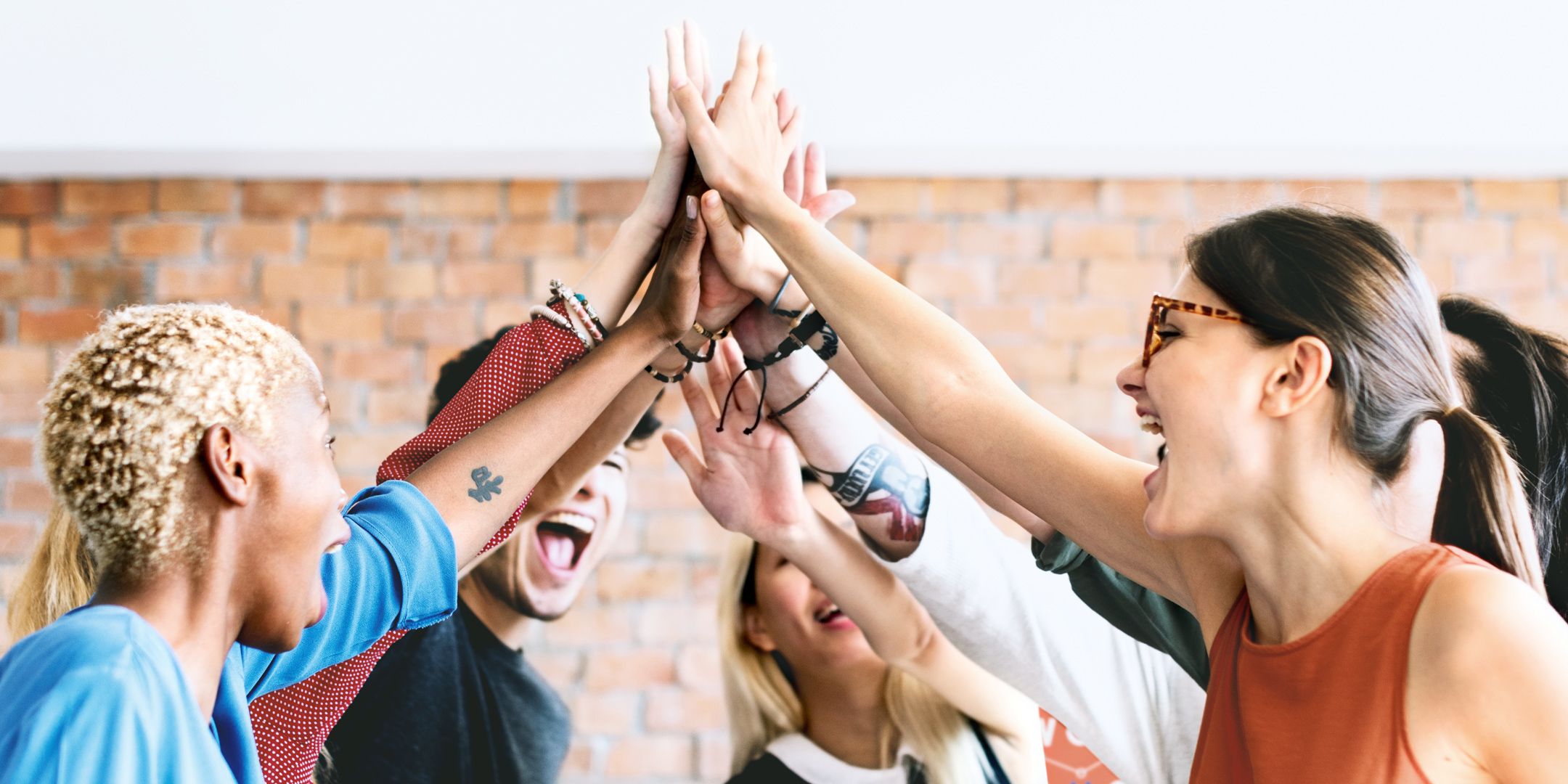 Several people are standing in a circle, laughing and giving each other high fives.